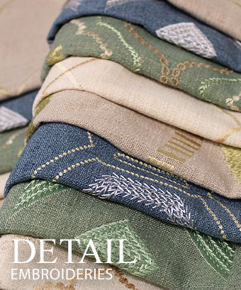 Layered stack of embroidered fabrics in blue, green, and neutral tones