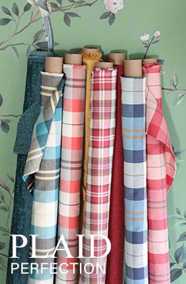 A variety of colorful plaid fabrics rolled on tubes against a floral background